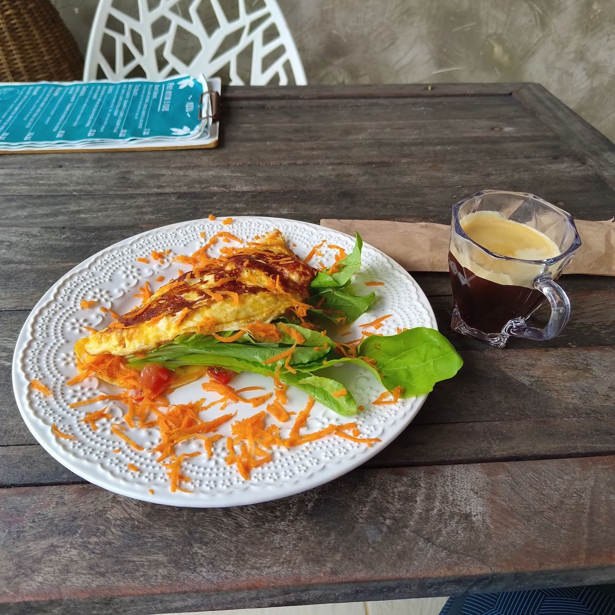 Omelete com ervas servido em prato branco ao lado do café